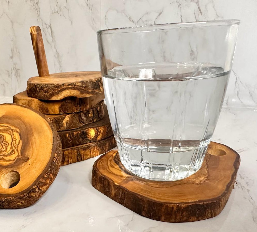 Clear glass of water on a wooden coaster with additional coasters in the background.